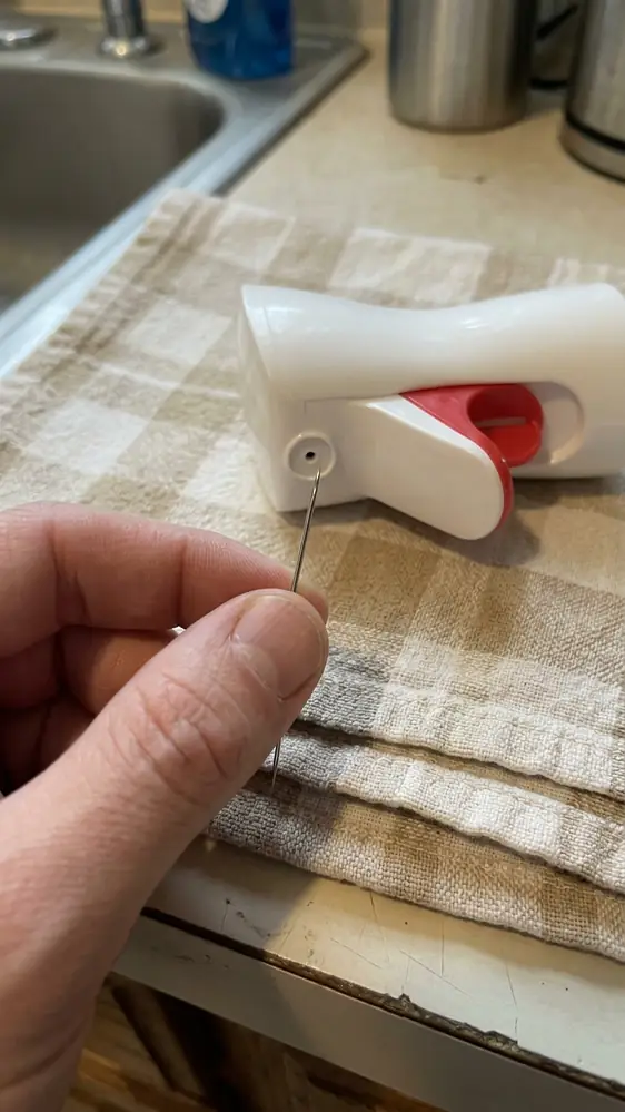 Oil Sprayer Not Working? 9 Fixes That Actually Restore the Mist 6 Fine sewing needle inserted straight and gently into the nozzle orifice of an oil sprayer head held under a light